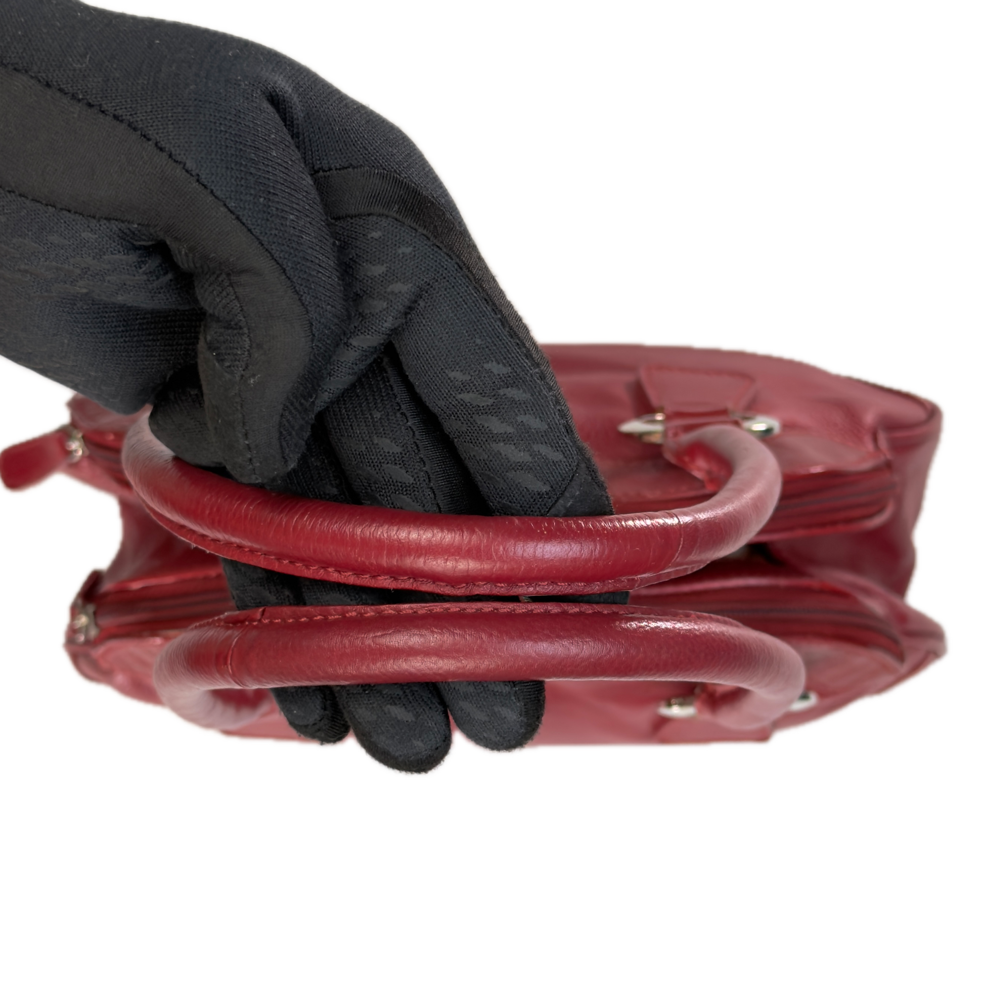 Handles of an elongated vintage Y2K Collection by Debenhams red genuine leather shoulder bag with silver hardware.