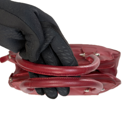 Handles of an elongated vintage Y2K Collection by Debenhams red genuine leather shoulder bag with silver hardware.