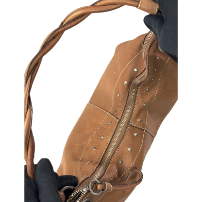 Vintage Fossil tan brown leather hobo bag featuring a braided shoulder strap, silver studs, and a signature key charm.