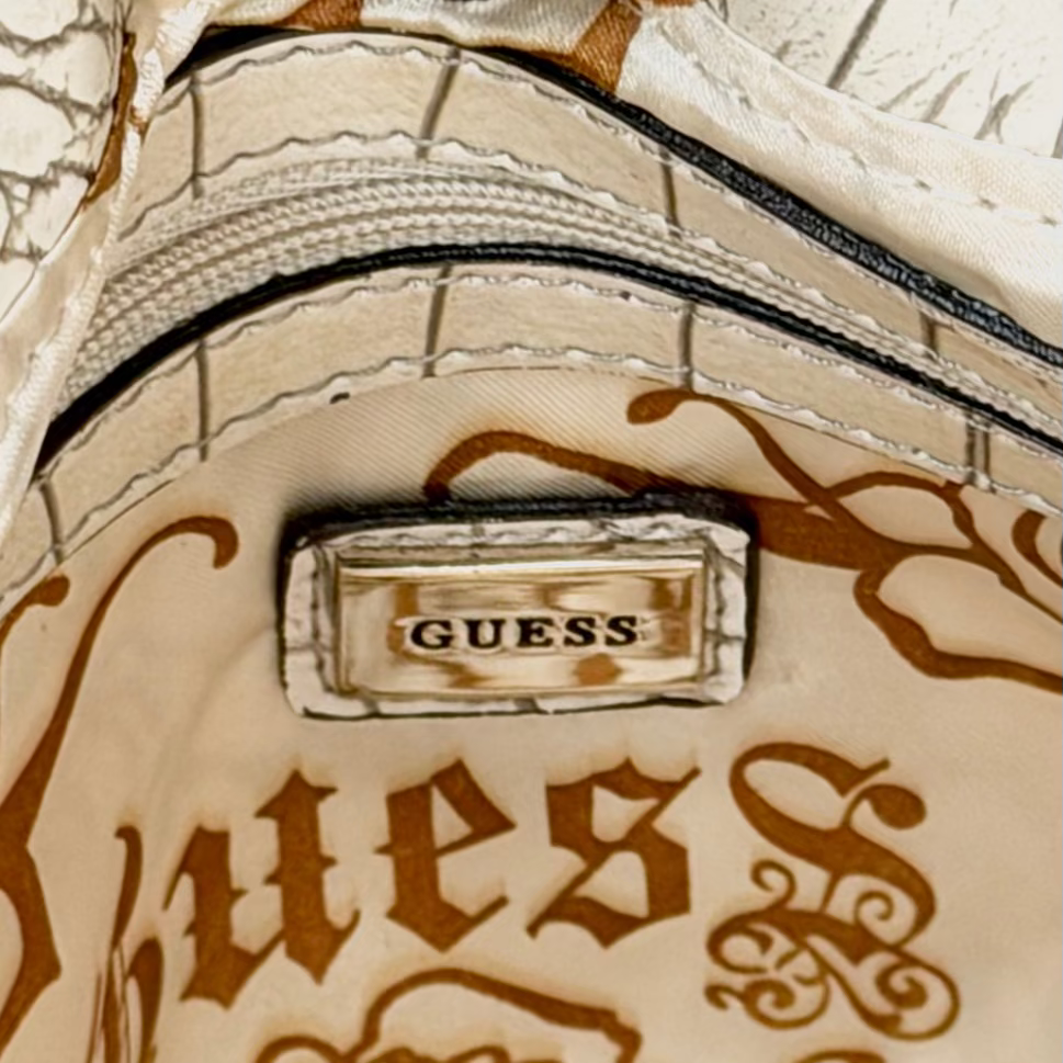 Vintage Guess slouchy hobo bag featuring a black, brown, and cream geometric pattern with a large silver G buckle closure.