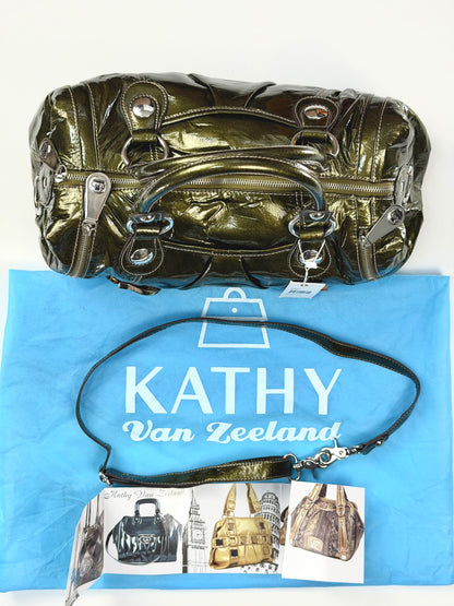 Metallic handbag on a blue surface with 'Kathy Van Zeeland' branding.