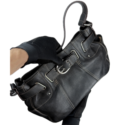 Vintage Tignanello black pebbled leather shoulder bag featuring a silver front buckle, contrast stitching, and side pockets.