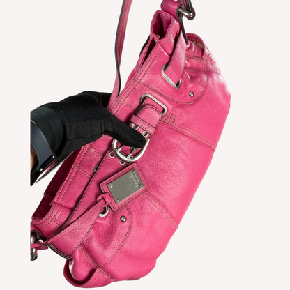 Vintage Y2K Tignanello hot pink pebbled leather shoulder bag featuring a statement silver front buckle, side slip pockets, and a branded metal hanging tag.