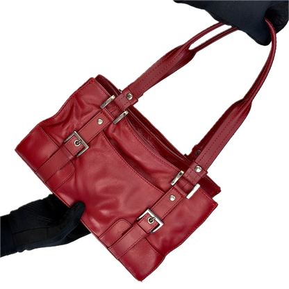 Front view of a structured vintage Y2K Collection by Debenhams glossy red shoulder bag featuring silver-tone buckle details against a black background.