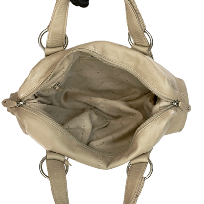 A Tula beige leather handbag shown open from a top-down view, displaying its interior lining and silver-tone metal hardware against a plain white background.
