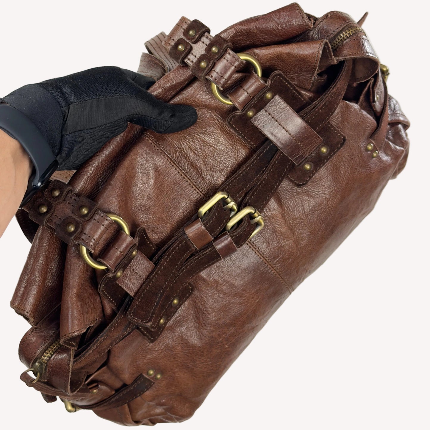 Close-up of the antique brass utilitarian hardware and distressed brown leather on a rare vintage Zippo archive bag."